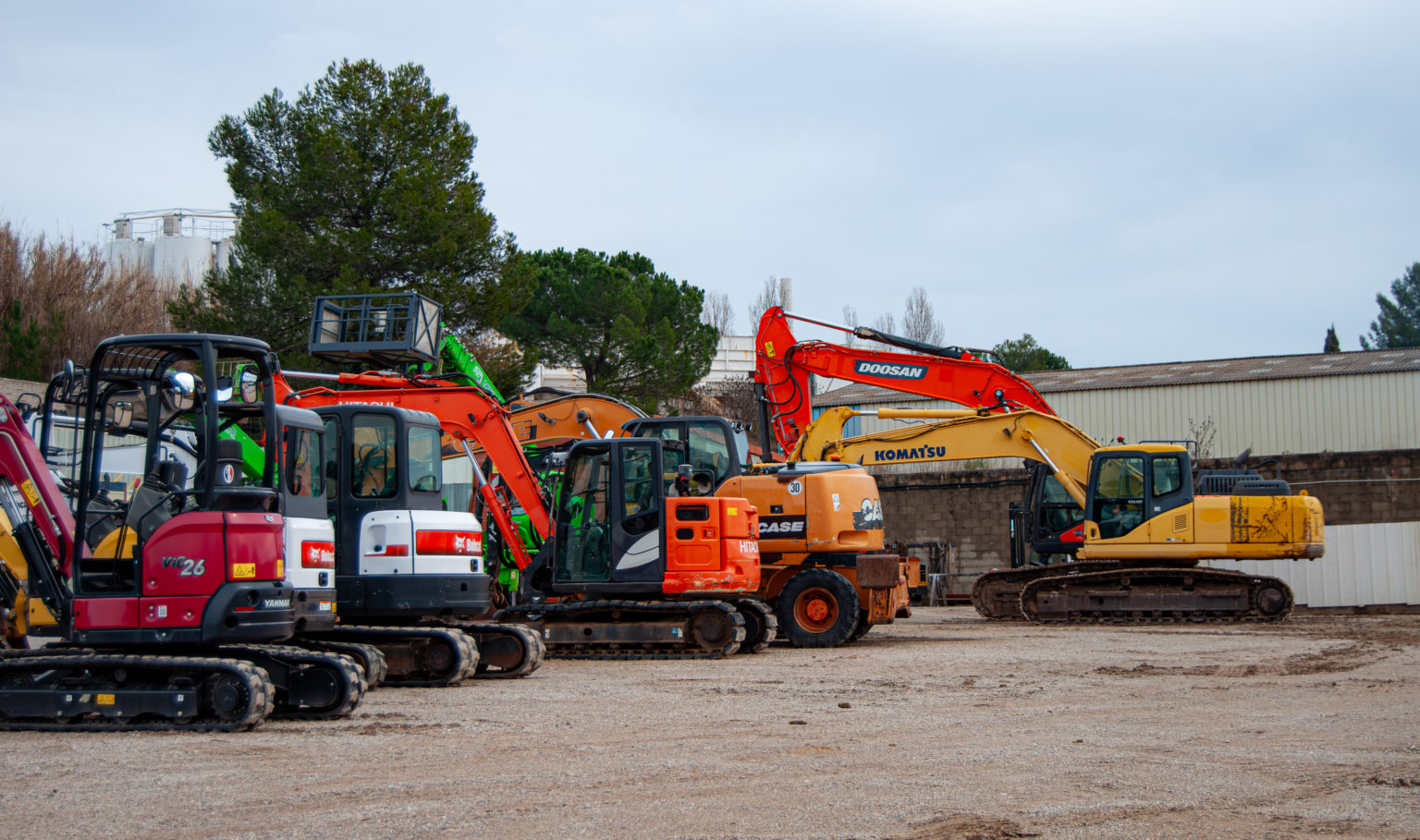Alignement de mini-pelles et pelles mécaniques de marques Yanmar, Hitachi, Case et Komatsu sur un parc de location.